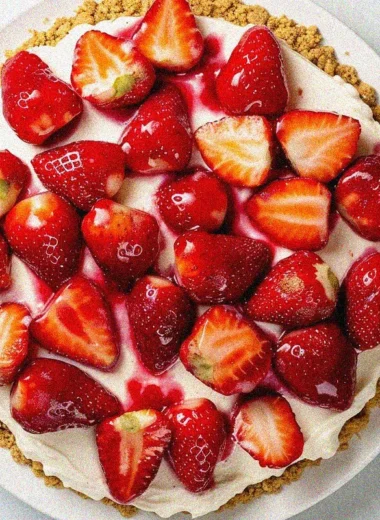 Overhead view of homemade strawberry cheese cake with fresh strawberry topping and creamy cheesecake filling on white plate