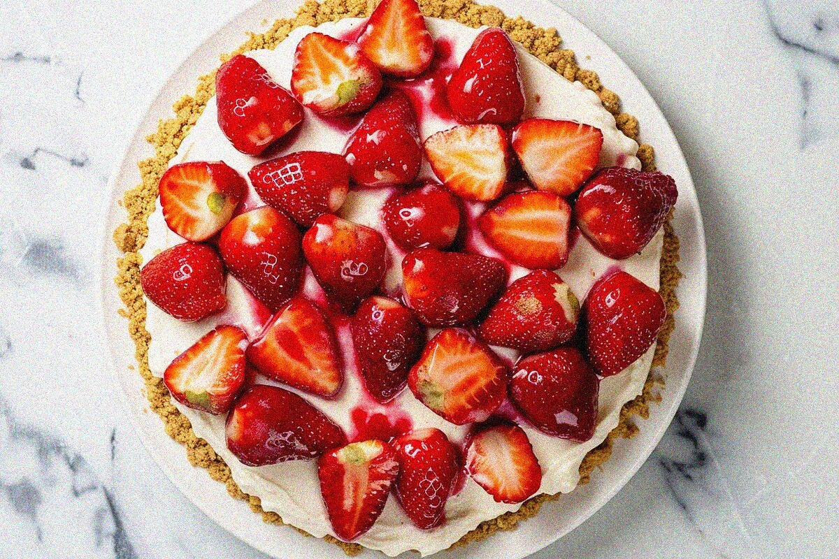 Overhead view of homemade strawberry cheese cake with fresh strawberry topping and creamy cheesecake filling on white plate